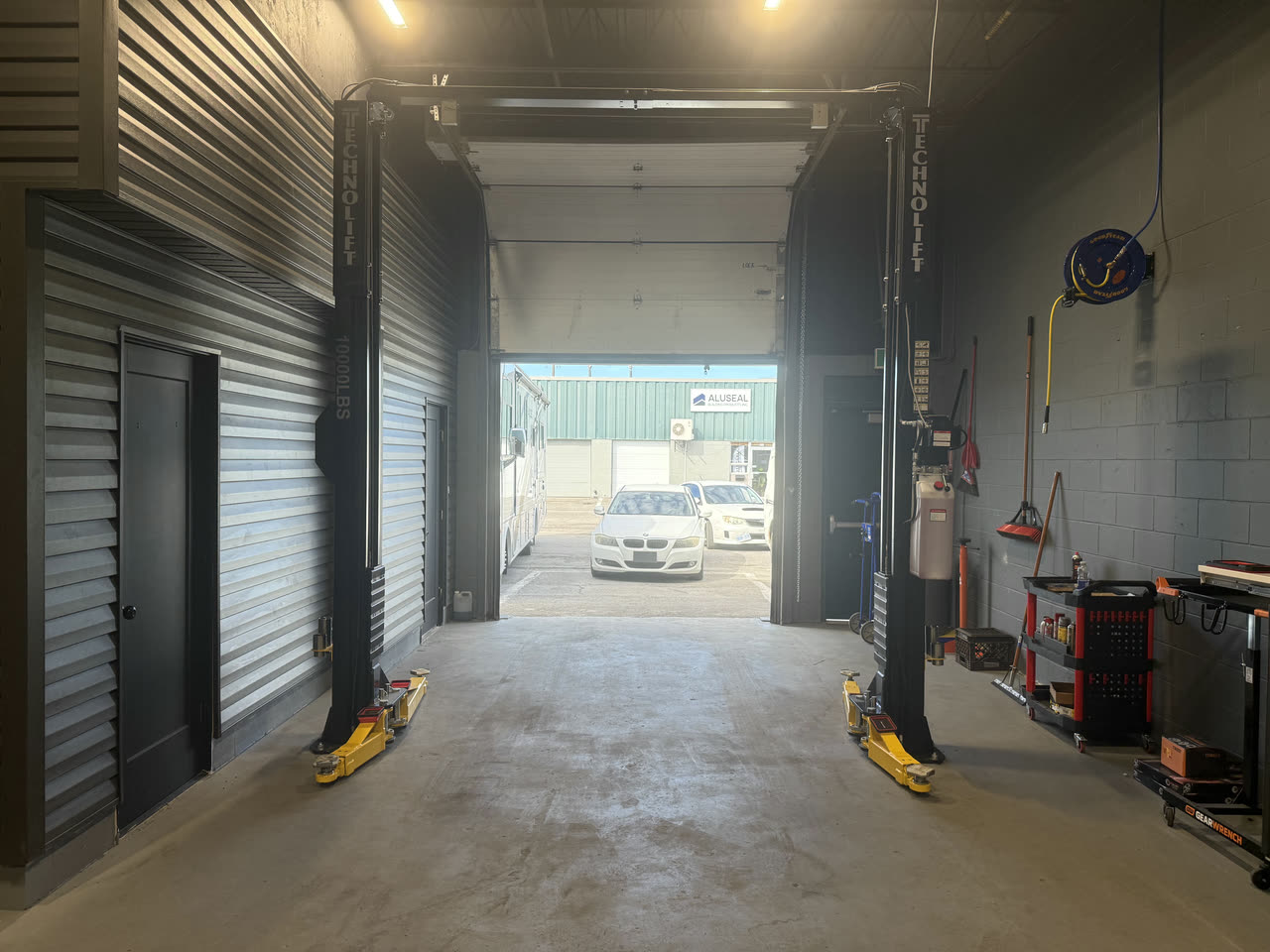The drive through bay between the two post lifts, bay door open to the lot