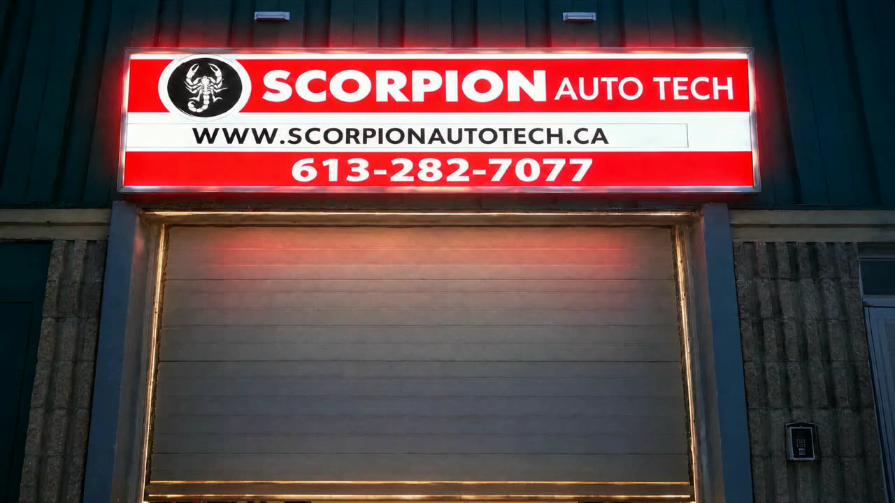 The Scorpion Auto Tech sign lit up over the bay door at night